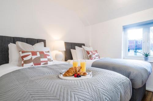 a bed with a plate of food and two glasses of orange juice at 3 BDR House in Kingston upon Thames, London Waterloo in 30 mins in Kingston upon Thames