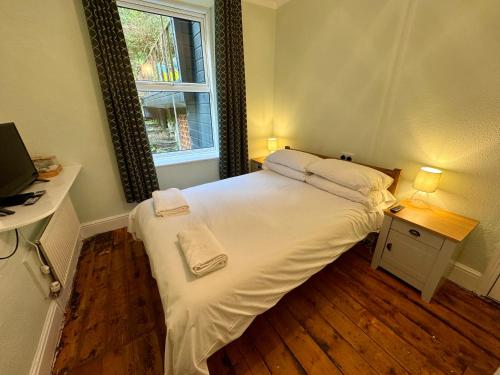 a bedroom with a large white bed with a window at Fairhaven Stay in Betws-y-coed