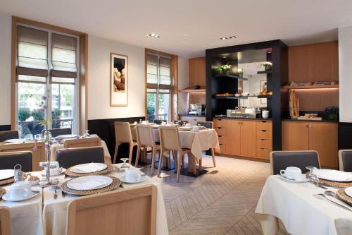 ein Restaurant mit Tischen und Stühlen und eine Küche in der Unterkunft Marceau Champs-Elysées in Paris