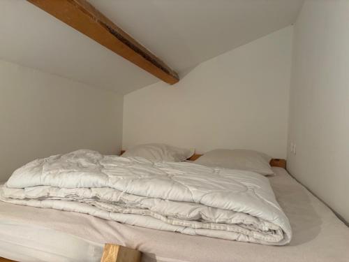 a bed with white sheets and pillows in a room at Les Balcons de L'Izoard in Arvieux