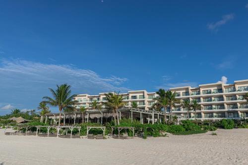 a hotel on the beach with chairs and palm trees at Palmaïa The House of AïA All Inclusive Wellness Resort in Playa del Carmen