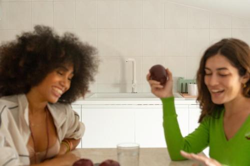 two women standing in a kitchen holding an apple at Spacebility Airport - self check-in in Cagliari