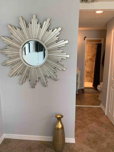 a mirror hanging on a wall with a vase at Quaint Coastal Pool Home on Florida's Space Coast in Melbourne