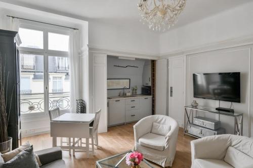un salon avec une télévision, une table et des chaises dans l'établissement Chic apartment on the Champs-Élysées with AC, à Paris