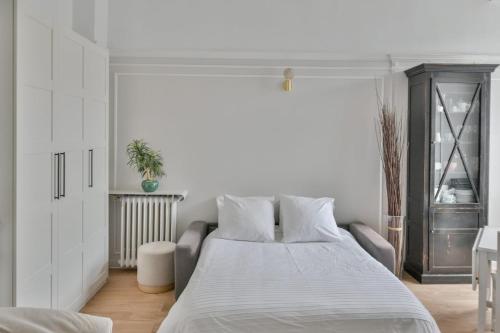 une chambre blanche avec un grand lit et une fenêtre dans l'établissement Chic apartment on the Champs-Élysées with AC, à Paris