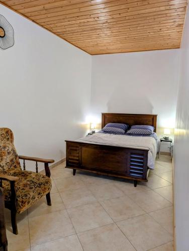 une chambre avec un grand lit et une chaise dans l'établissement La Ferme Des Pierrettes, à Menneville