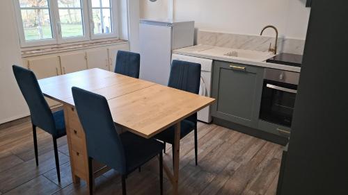 une cuisine avec une table en bois et des chaises bleues dans l'établissement Appartement 2 à 4 personnes à la campagne, à Perrecy-les-Forges