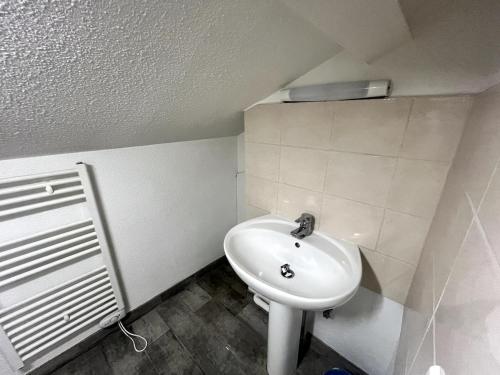 La salle de bains est pourvue d'un lavabo blanc et d'un radiateur. dans l'établissement Montferrand Dortoir, à Clermont-Ferrand
