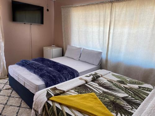 a bedroom with a bed with a tv on the wall at Savannah Guest House Mafikeng in Mahikeng