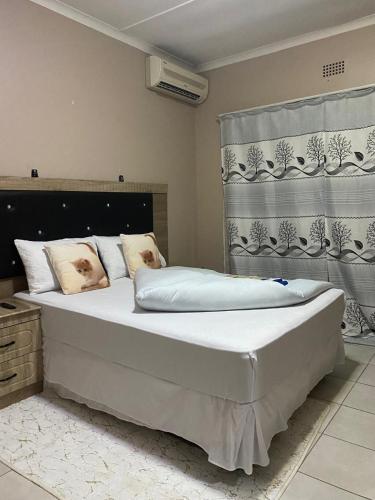 a large bed in a bedroom with a curtain at Savannah Guest House Mafikeng in Mahikeng