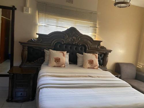 a large bed with a large wooden headboard and pillows at Savannah Guest House Mafikeng in Mahikeng