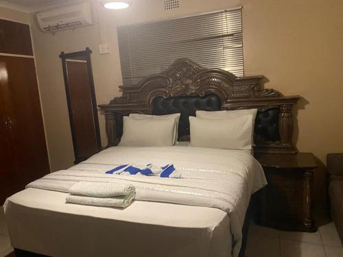 a bed with a wooden headboard with blue bows on it at Savannah Guest House Mafikeng in Mahikeng