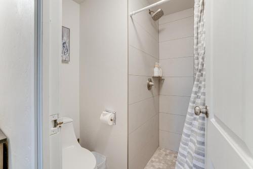a white bathroom with a shower and a toilet at Frisco Condo with Pool Access Walk to Main Street! in Frisco