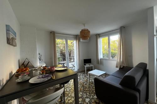 een woonkamer met een bank en een tafel bij La Mimosette Joli appartement 1 chambre tout confort proche de la plage in Le Grau-du-Roi