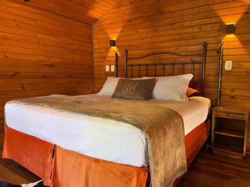 a bedroom with a bed in a wooden cabin at Hotel Cabanas Glamour in Gramado