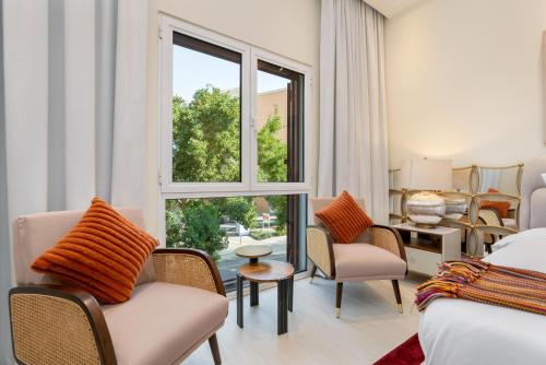 a hotel room with a bed and chairs and a window at White Sage Incredible Studio Next to Metro in Dubai