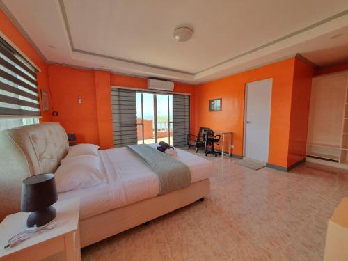 a bedroom with a large bed and orange walls at Simala Beach House Beachfront 4BR Retreat by the Sea in Sibonga