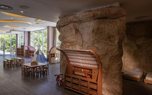 a room with a stone wall with tables and chairs at Palmaïa The House of AïA All Inclusive Wellness Resort in Playa del Carmen
