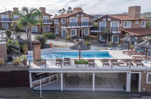 a house with a swimming pool with tables and chairs at Soles del lago in Villa Carlos Paz