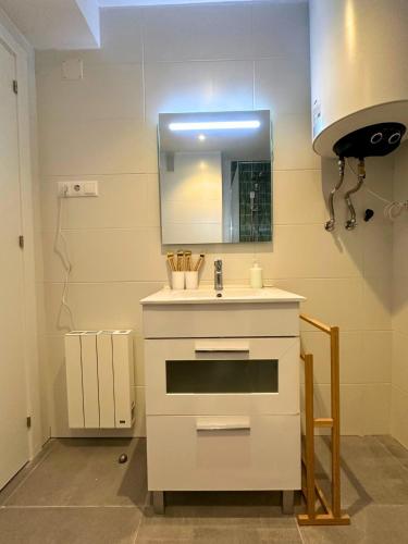 a white kitchen with a sink and a mirror at Apartamento Anayet: Formigal Centro in Formigal