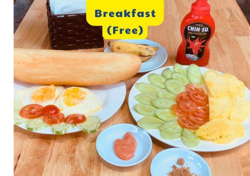 a table with plates of food with tomatoes and a hot dog at Tam Coc Lavender Homestay -Authentic Ninh Binh Experiences in Ninh Binh