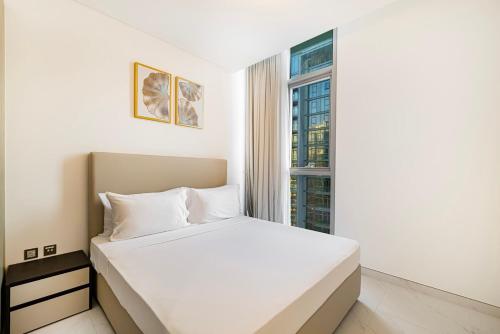 a white bed in a room with a window at Luxury 2BR Prime Location & Burj Views in Dubai