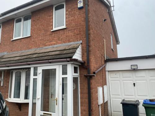 a red brick house with a white garage at La ap in Wednesbury