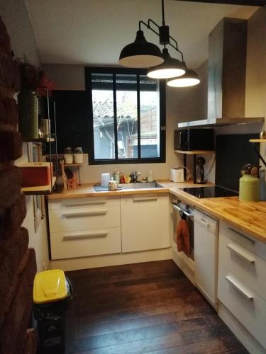 une cuisine avec des armoires blanches et une fenêtre dans l'établissement Maison 2 chambres centre ville, à Toulouse