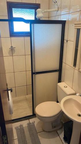 a bathroom with a shower and a toilet and a sink at Pousada Granada in Rio das Ostras