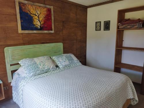 Un dormitorio con una cama y un cuadro en la pared. en Cabaña Canto del Zorzal, en Villarrica