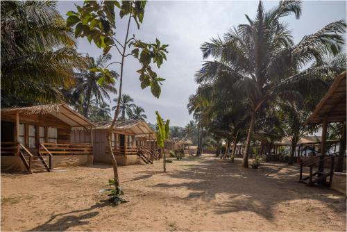 a village with houses and palm trees on a dirt road at Ravi Yoga Retreat in Polem