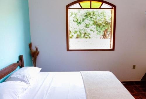 a bedroom with a white bed and a window at Pousada Manga Rosa in Serra do Cipo