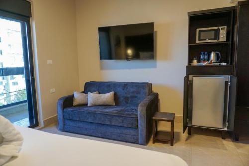 a blue couch in a room with a tv at Mizirawi Historic Hotel in Ramallah