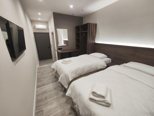 a hotel room with two beds and a flat screen tv at D Suites & Rooms in Ioannina