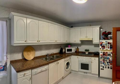 eine Küche mit weißen Schränken und einer Spüle in der Unterkunft Apartamento en Oviedo in Oviedo