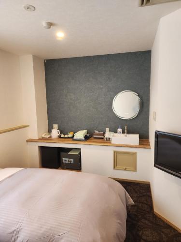 a bedroom with a bed and a sink and a mirror at Hakuba Hotel Hana-no-Sato in Hakuba