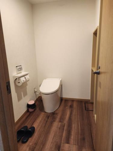 a bathroom with a toilet and a pair of shoes at Hakuba Hotel Hana-no-Sato in Hakuba