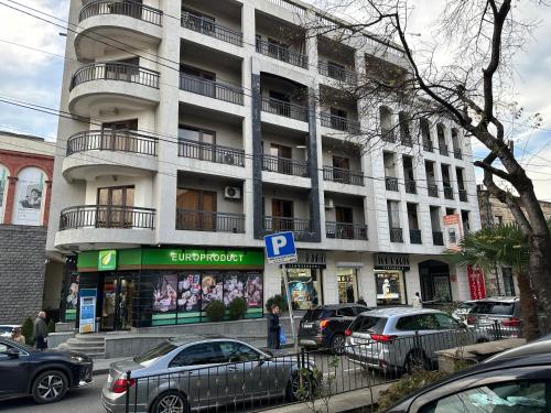 Un gran edificio blanco con coches aparcados delante. en central square, en Kutaisi