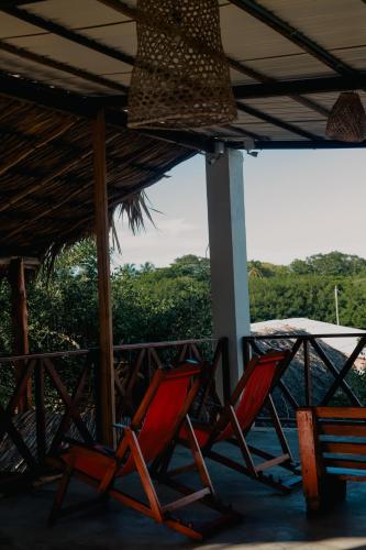 two red chairs sitting on a porch with a table at Hostal Casa en la Ciénaga Rincon del Mar in Rincón