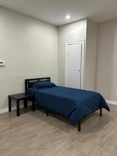 a bedroom with a bed with a blue blanket and a table at H men's dormitory in Hamilton