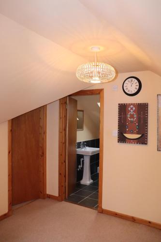 ein Badezimmer mit einem Waschbecken und einer Uhr an der Wand in der Unterkunft CrAgMhOr Bed & Breakfast In Balquhidder Glen in Lochearnhead