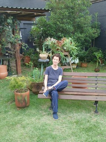 a woman sitting on a bench in a garden at Pousada Preamare in Ubatuba