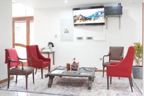 a living room with red chairs and a tv at Colca Canyon Hotel by PERU HTL in Chivay