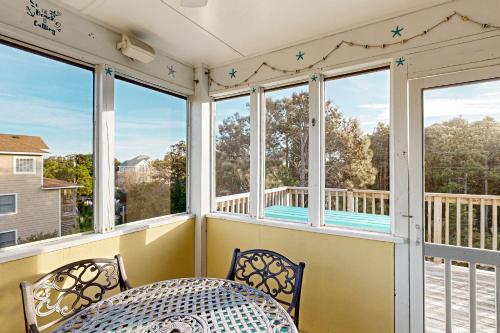 a screened porch with a table and chairs and windows at Play Time in Waves