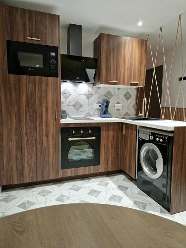une cuisine avec des armoires en bois et une laveuse et une sécheuse dans l'établissement Charmant Appartement Climatisé Centre Ville 4 Personnes, à Ajaccio