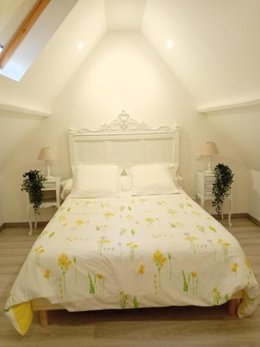 - une chambre avec un lit blanc orné de fleurs jaunes dans l'établissement Le Murmure de la petite Oasis, à Neslette