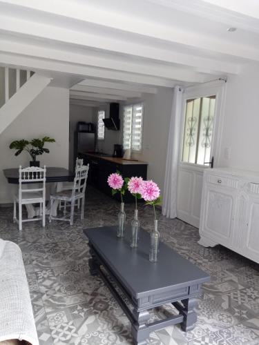 - un salon doté d'une table avec des vases et des fleurs dans l'établissement Le Murmure de la petite Oasis, à Neslette