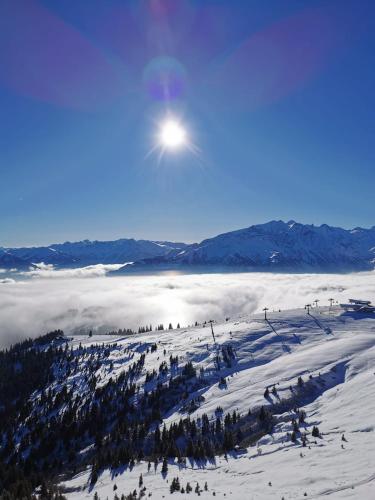 a view of a snowy mountain with the sun in the sky at Apartment Auszeit Sommercard inklusive in Hollersbach im Pinzgau
