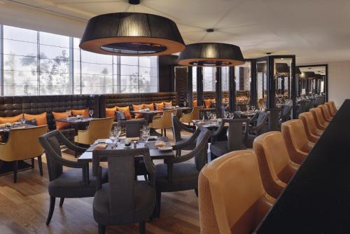 a dining room with tables and chairs and large windows at Voco - Riyadh by IHG in Riyadh