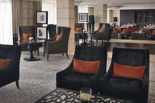 a lobby with chairs and tables and a restaurant at Voco - Riyadh by IHG in Riyadh